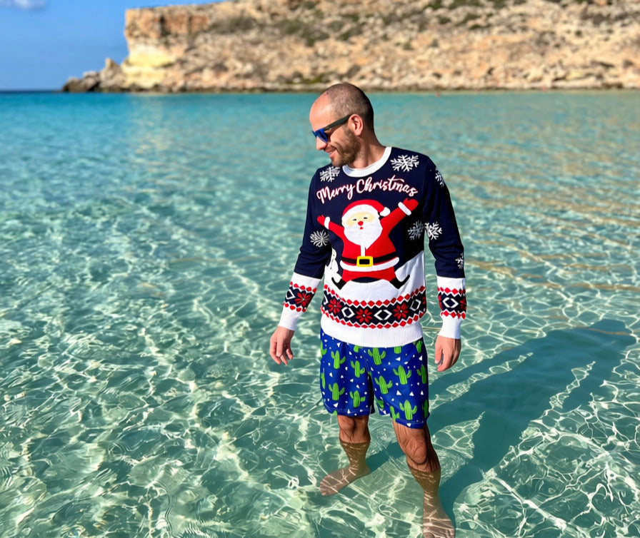 Persona che fa il bagno nel mare di Lampedusa indossando un maglione natalizio per la Teoria della Stagione Sbagliata.